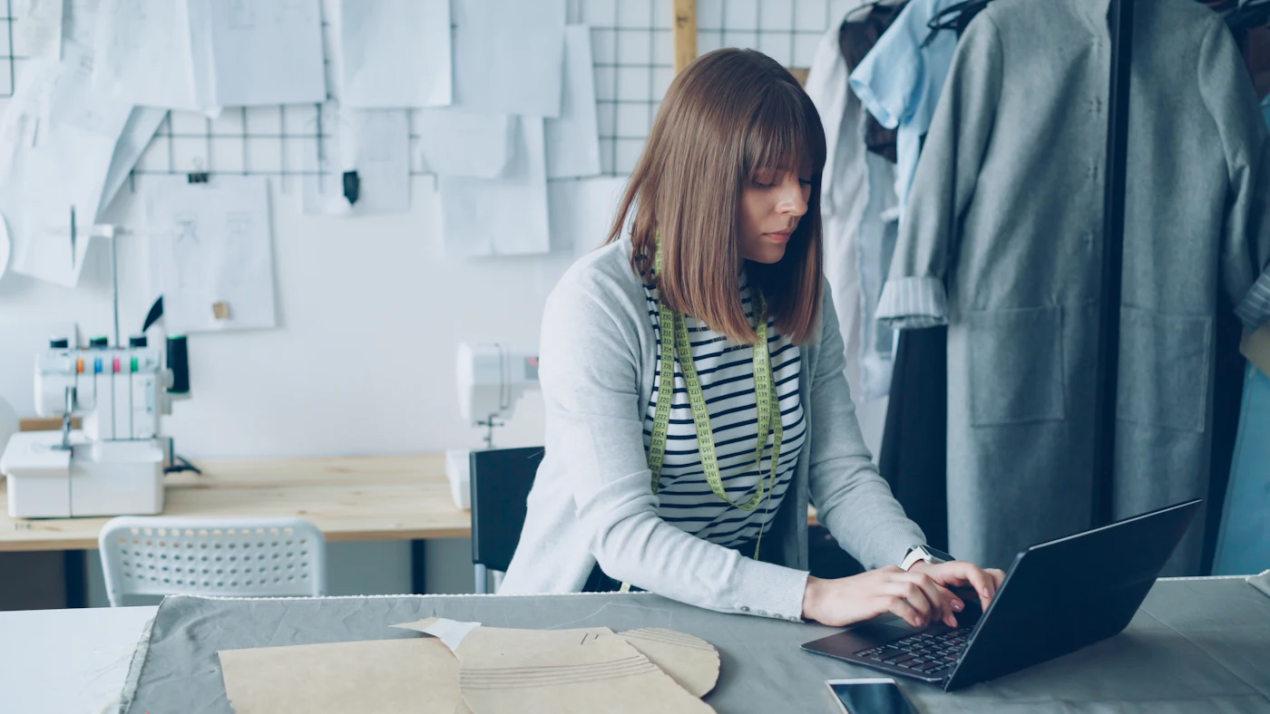 Representative small-business owner working on a laptop in a clothing studio